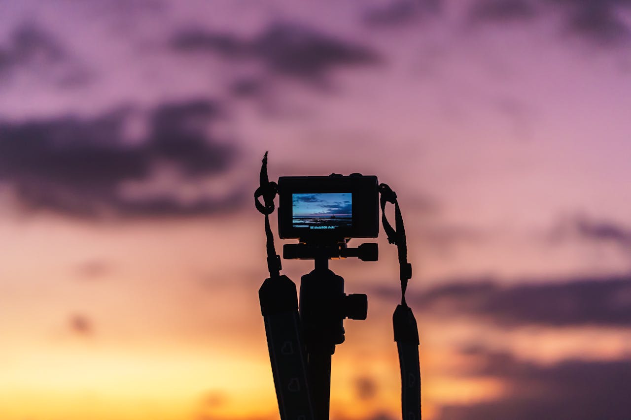 Camera silhouette capturing a vibrant and colorful sunset with a dramatic sky.